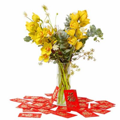 Yellow orchids in a vase with red envelopes scattered around.