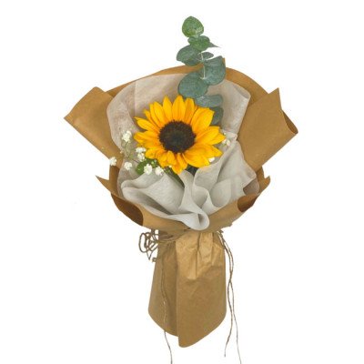 A single sunflower bouquet with eucalyptus and baby's breath, wrapped in brown paper.