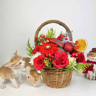 Floral arrangement in a basket with kittens and a snowman.