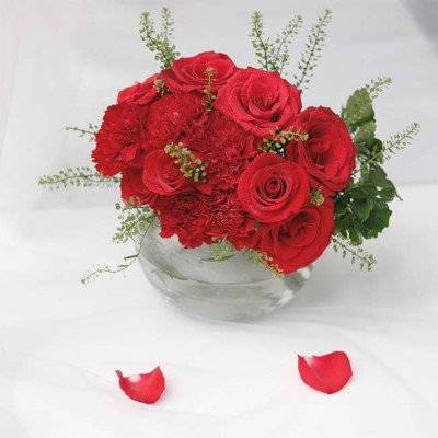 Red roses and carnations in a glass vase.