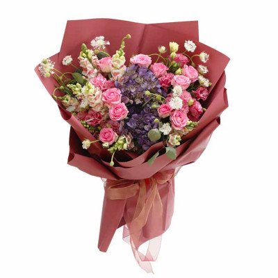 A lush bouquet of pink and purple flowers wrapped in deep red paper and tied with a ribbon.