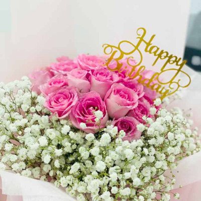 Pink roses and baby's breath bouquet with a "Happy Birthday" topper.