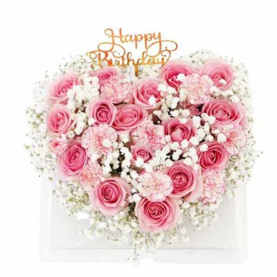 Heart-shaped floral cake with pink roses, carnations, baby's breath, and "Happy Birthday" topper.
