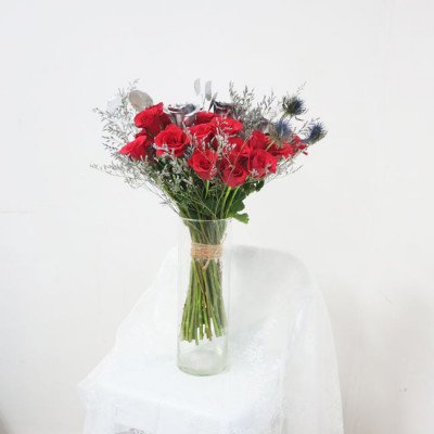 A bouquet of red roses and silver flowers in a glass vase.