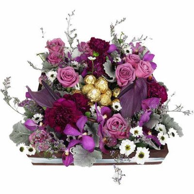 A wooden box of purple roses, carnations, orchids, and other flowers, with Ferrero Rocher chocolates.