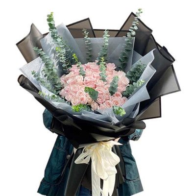 Bouquet of pink roses and eucalyptus, wrapped in black and grey paper, tied with a cream ribbon.