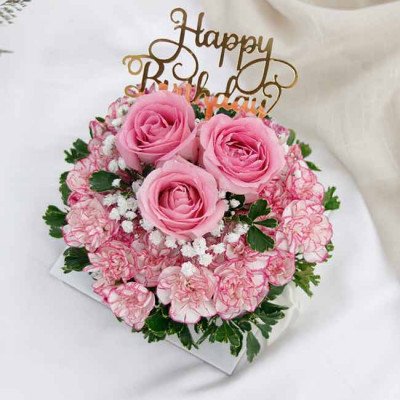 Pink roses and carnations in a box with "Happy Birthday" banner.