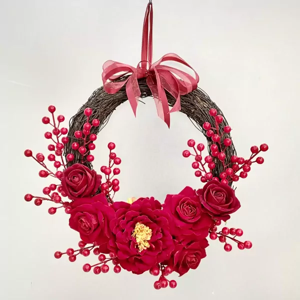 A red rose and berry wreath with a red ribbon bow.