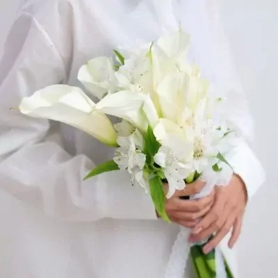 Bride holding a white bouquet of calla lilies and alstroemeria with lace.