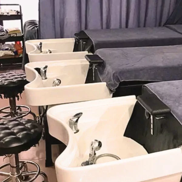 Hair salon washing stations with reclining chairs and stools.
