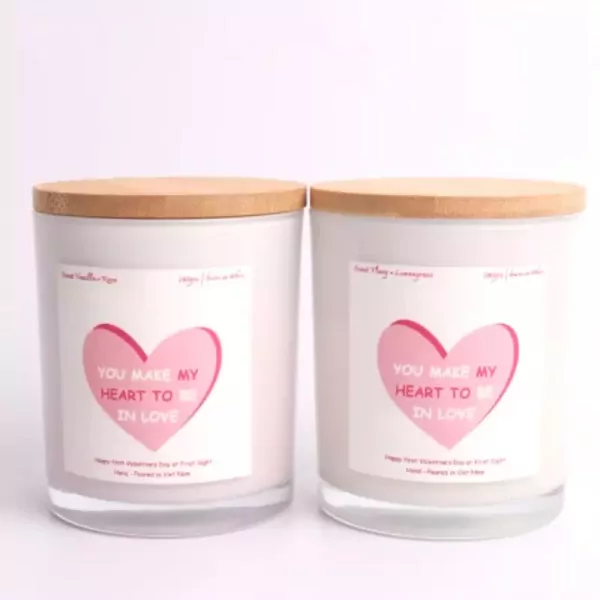 Two white candles with bamboo lids, featuring pink heart labels that say "You make my heart to be in love".