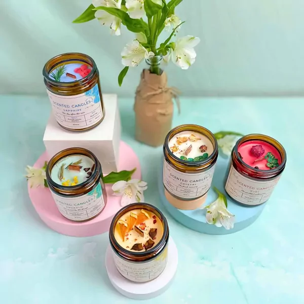 Scented candles in amber jars with decorative elements, arranged on colorful stands with flowers.