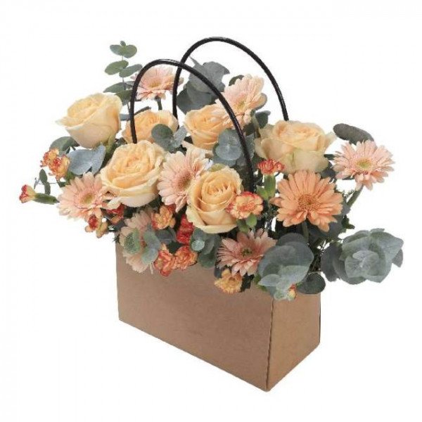 Peach roses, gerbera daisies, and carnations in a cardboard gift bag with black handles.