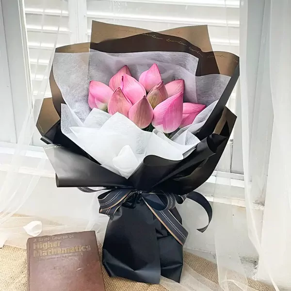 Bouquet of pink lotus flowers with decorative wrapping and ribbon.