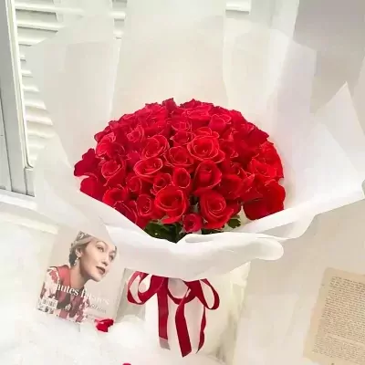 A large bouquet of 66 red roses wrapped in white paper, tied with a red ribbon.