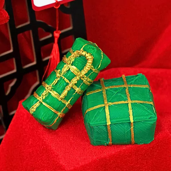Green bánh chưng and bánh tét shaped scented wax decorations with gold accents.