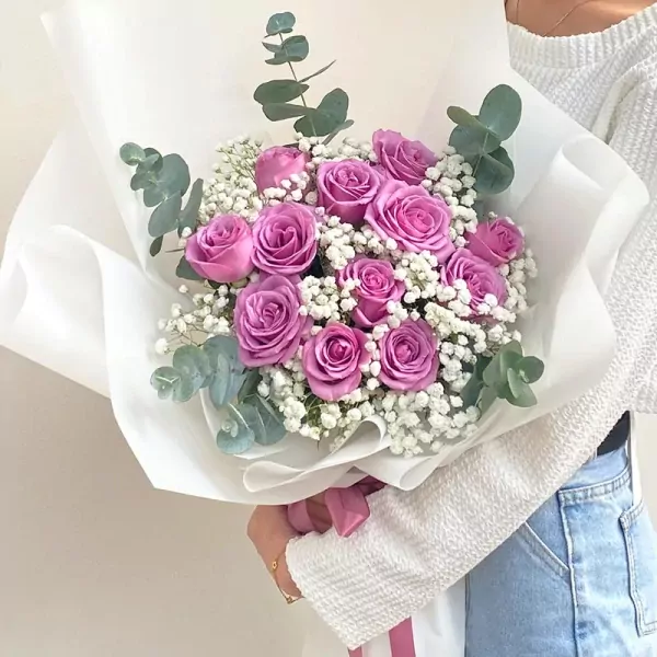 Bouquet of purple roses, baby's breath, and eucalyptus.