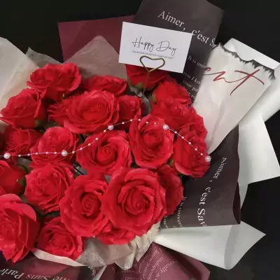 A bouquet of red roses with a "Happy Day" card and pearl beading.