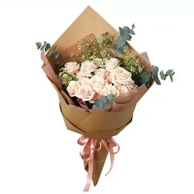 Bouquet of light pink roses with baby's breath and eucalyptus, wrapped in brown paper and tied with a pink ribbon.