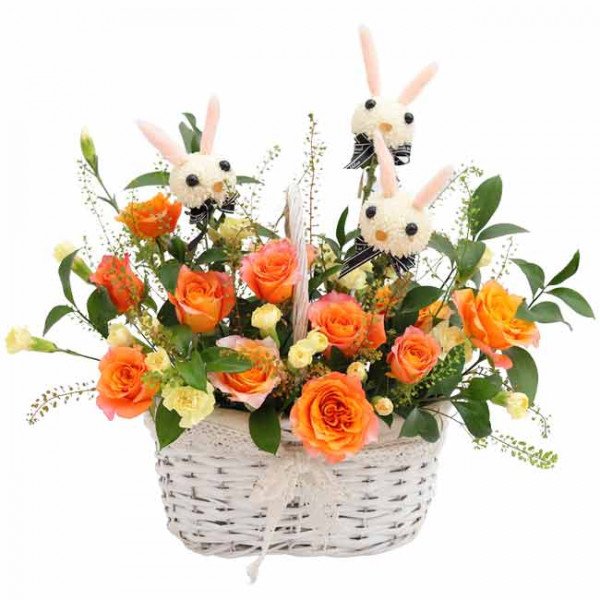 White basket of orange roses and yellow flowers with three bunny decorations.