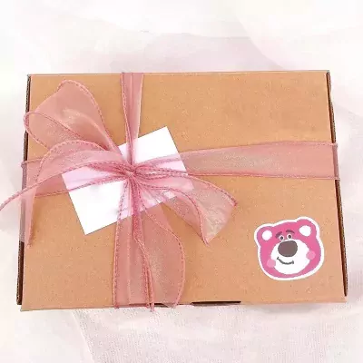 A brown gift box with a pink ribbon and bow, a white tag, and a Lotso bear sticker.