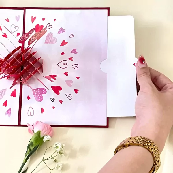 A 3D pop-up card with many hearts, a pink carnation, and baby's breath.