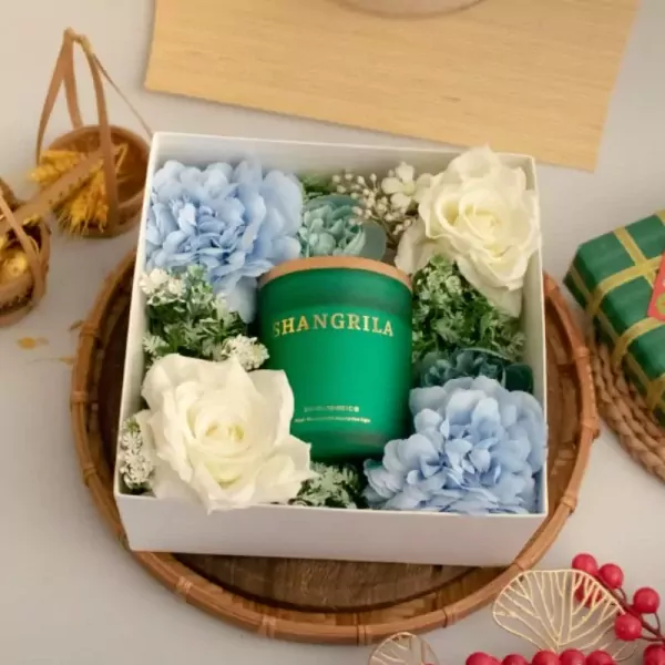 Gift box with green Shangrila candle, blue and white flowers, and golden wheat stalks.