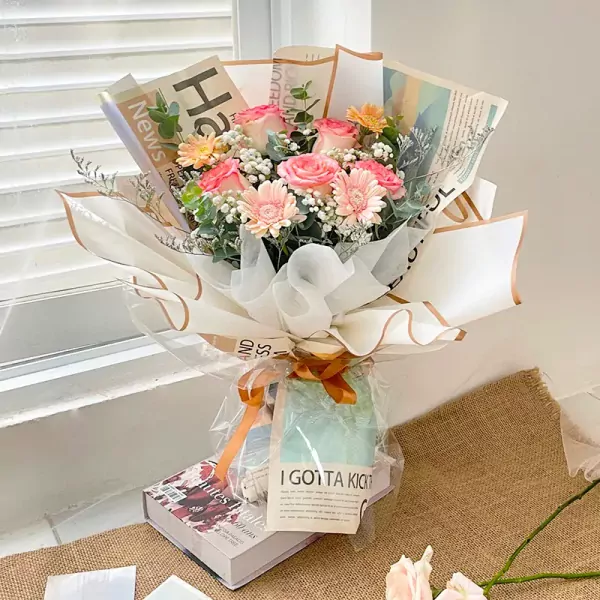 Bouquet of pink roses, gerbera daisies, and baby's breath wrapped in newspaper.