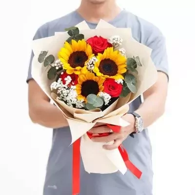 Man holding a bouquet of sunflowers and red roses with baby's breath and greenery.