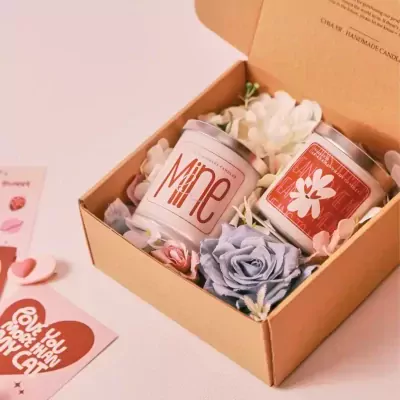 Gift box with two scented candles, flowers, and Valentine's Day cards.