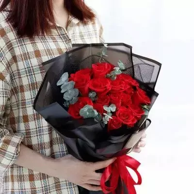 A bouquet of red roses wrapped in black paper, tied with a red ribbon.
