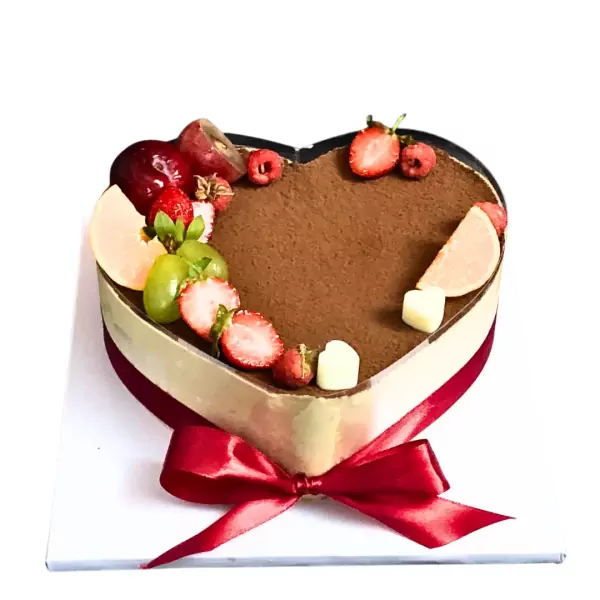 Heart-shaped tiramisu cake decorated with strawberries, grapes, raspberries, and white chocolate cubes.