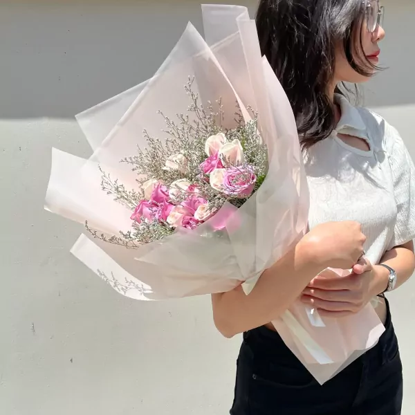 Woman holding a pastel pink and white rose bouquet.