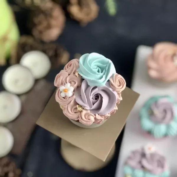Cupcakes decorated with pastel frosting roses and a small white flower.
