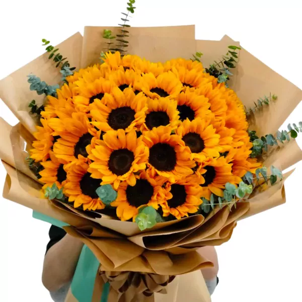 A large bouquet of sunflowers wrapped in brown paper with eucalyptus leaves.