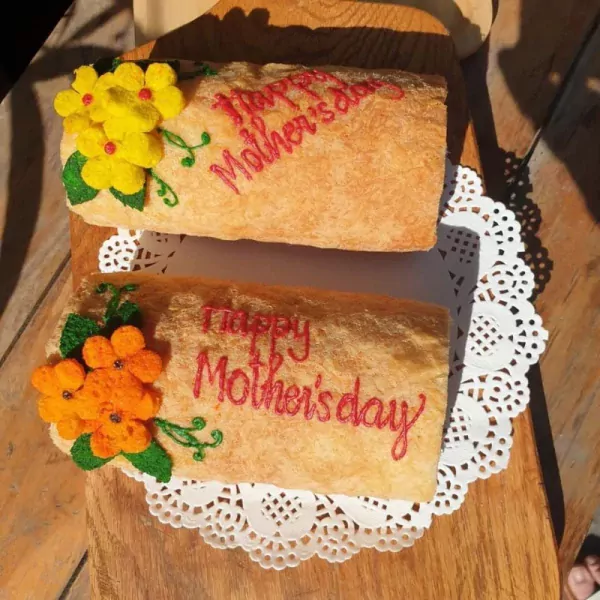Two egg floss rolls decorated with flowers and "Happy Mother's Day" in red icing.