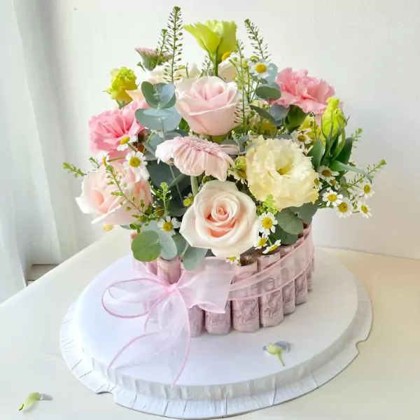 Flower arrangement with rolled banknotes around the base, adorned with pink roses, carnations, and daisies.