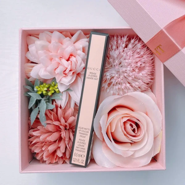 Gucci lipstick in a pink gift box with floral decorations.