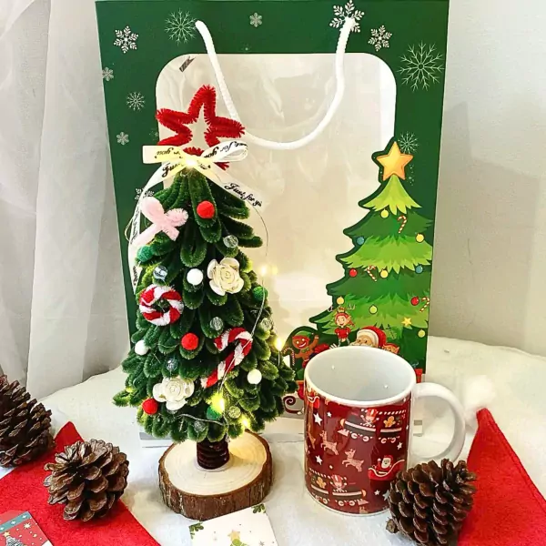 Cozy Christmas gift set with mini tree, mug, pinecones, and gift bag.