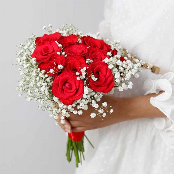 Bridal bouquet of red roses and baby's breath with a red ribbon.