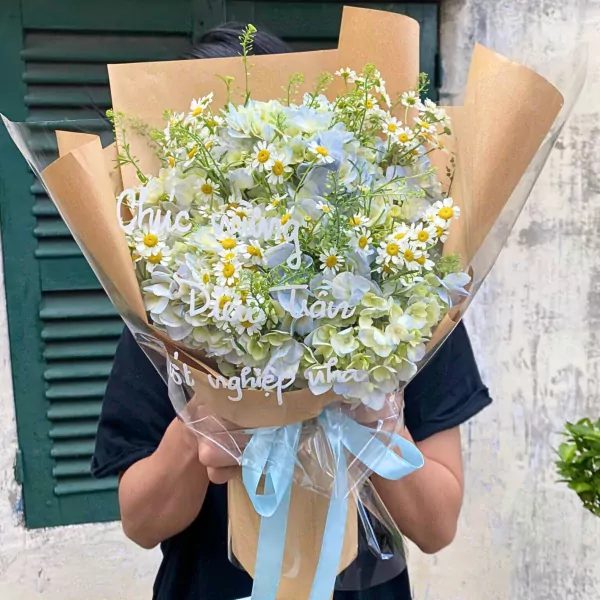 A bouquet of white daisies and blue hydrangeas with a personalized message.