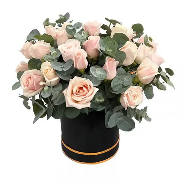 A round black box filled with light pink roses and eucalyptus leaves.