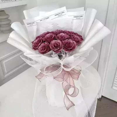 Amethyst Pink bouquet with deep pink roses, white wrapping, and a pink ribbon.