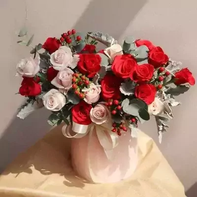 Pink and red roses in a light pink box, tied with a ribbon.