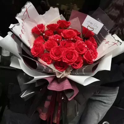 Bouquet of red roses with a "Happy Day" card and pearl accents.