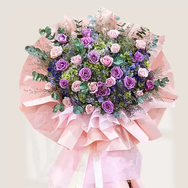 A glamorous flower stand with purple and cream roses, hydrangeas, and eucalyptus.