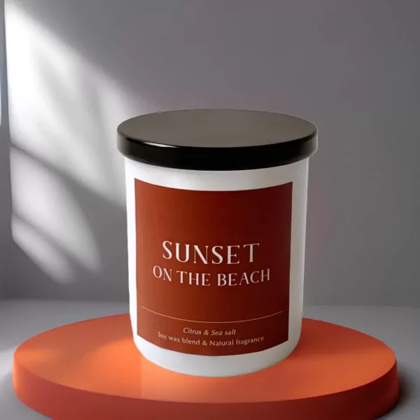 White candle with "Sunset On The Beach" label on an orange stand.