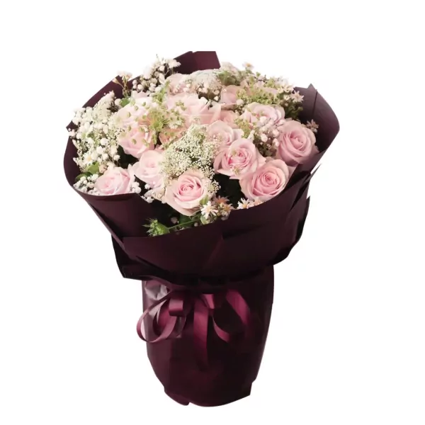 A bouquet of light pink roses and baby's breath wrapped in dark burgundy paper, tied with a ribbon.