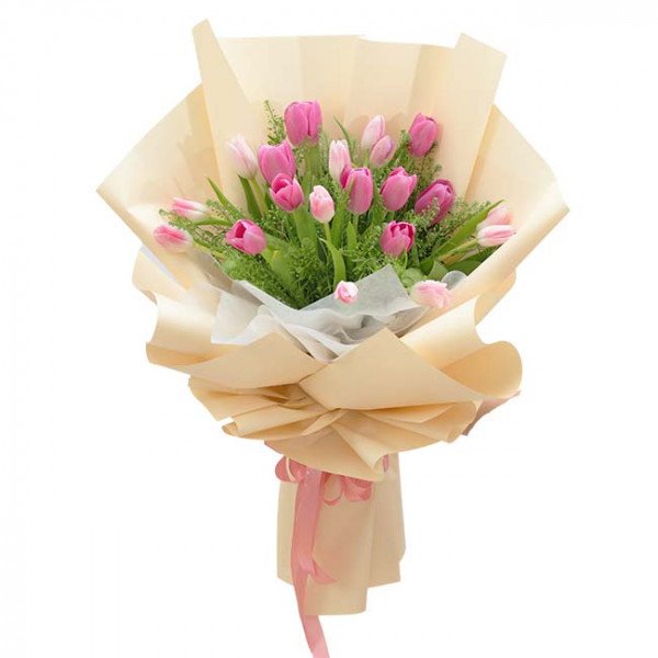Pink and light pink tulips in a bouquet wrapped in cream and tan paper with a pink ribbon.