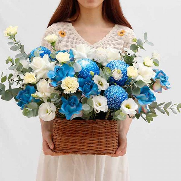 Basket of blue and white flowers including chrysanthemums, roses, and carnations.